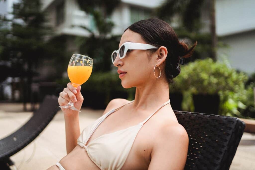 A woman holding a glass while wearing a bikini