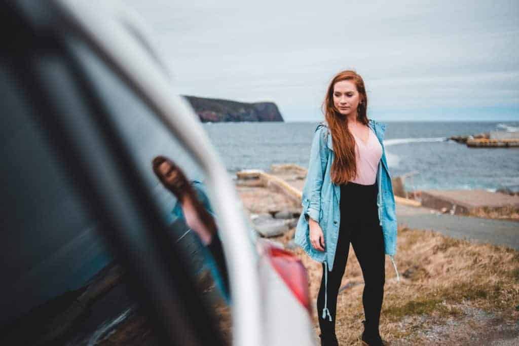 A person wearing black leggings at the back of a car