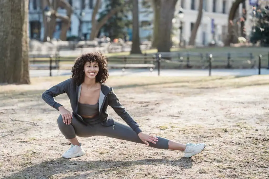 A woman wearing leggings stretching outdoors