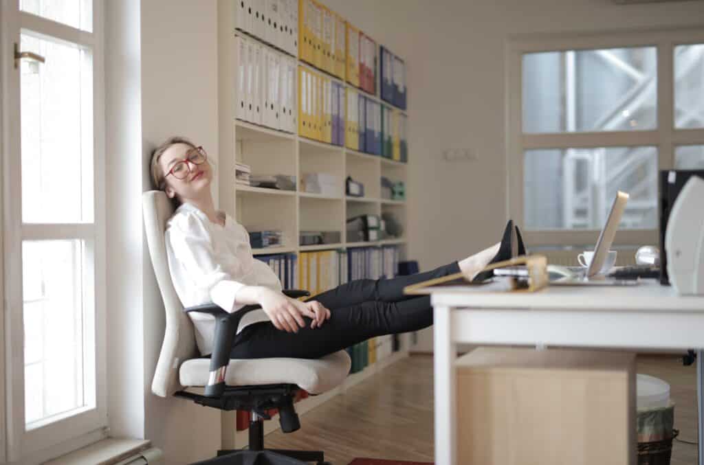 A woman in work with feet on table displaying leggings