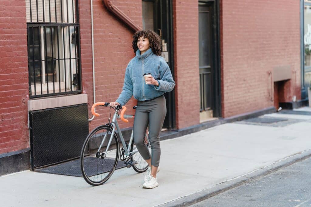 A woman wearing leggings bringing a bicycle to work