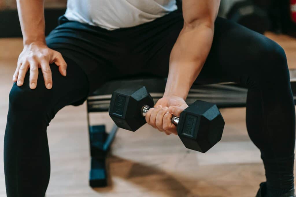 a man wearing black leggins holding a dumbell