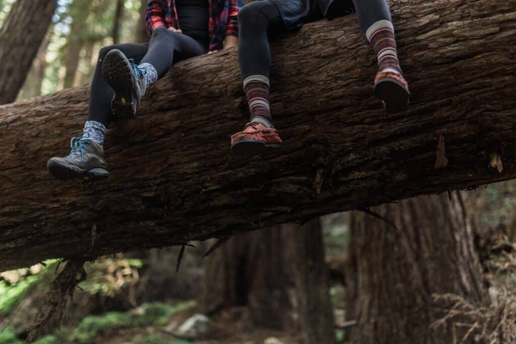 two people sitting on a tree wearing socks with leggings
