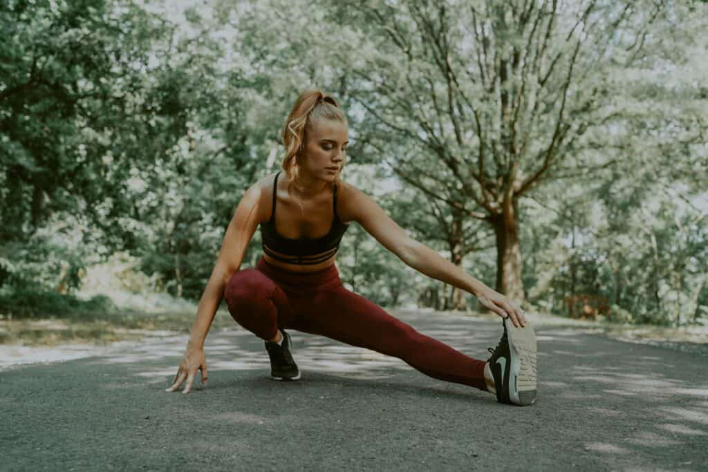 a woman stretching her toes wearing a maroon leggings