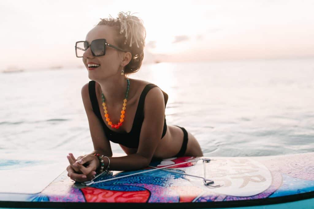 A woman leaning on a surf board on the beach