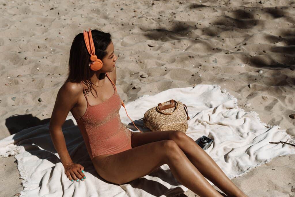 a woman sunbathing wearing an orange one piece swimsuit