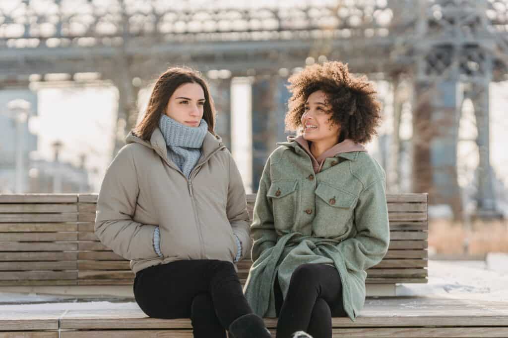 2 women sitting on a bench wearing black leggings