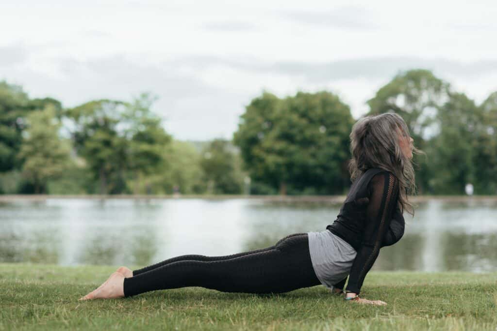 a woman stretching on the grass wearing black leggings