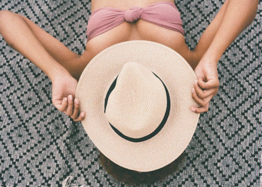 a woman holding a hat wearing a bandeau bikini top