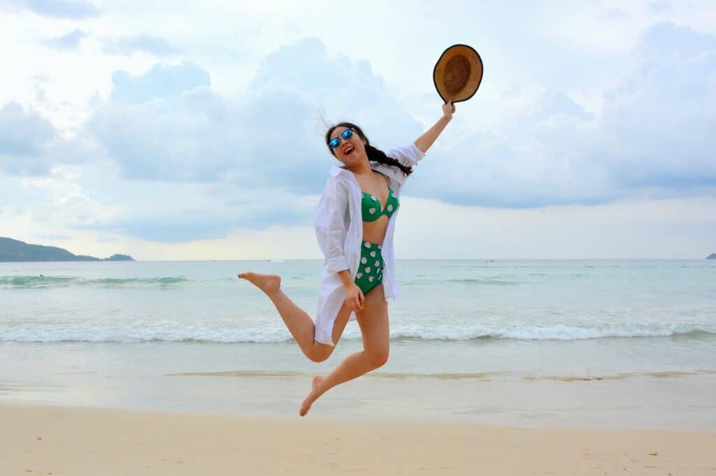 a woman jumping on the shore wearing a polka dot bikini