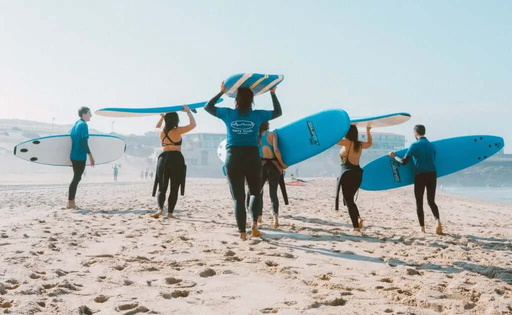 Group of surfers on the beach all holding their matching blue and white surfboards