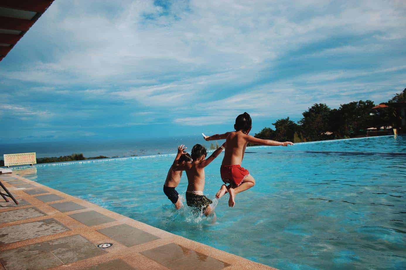 three kids jumping on the swimming pool