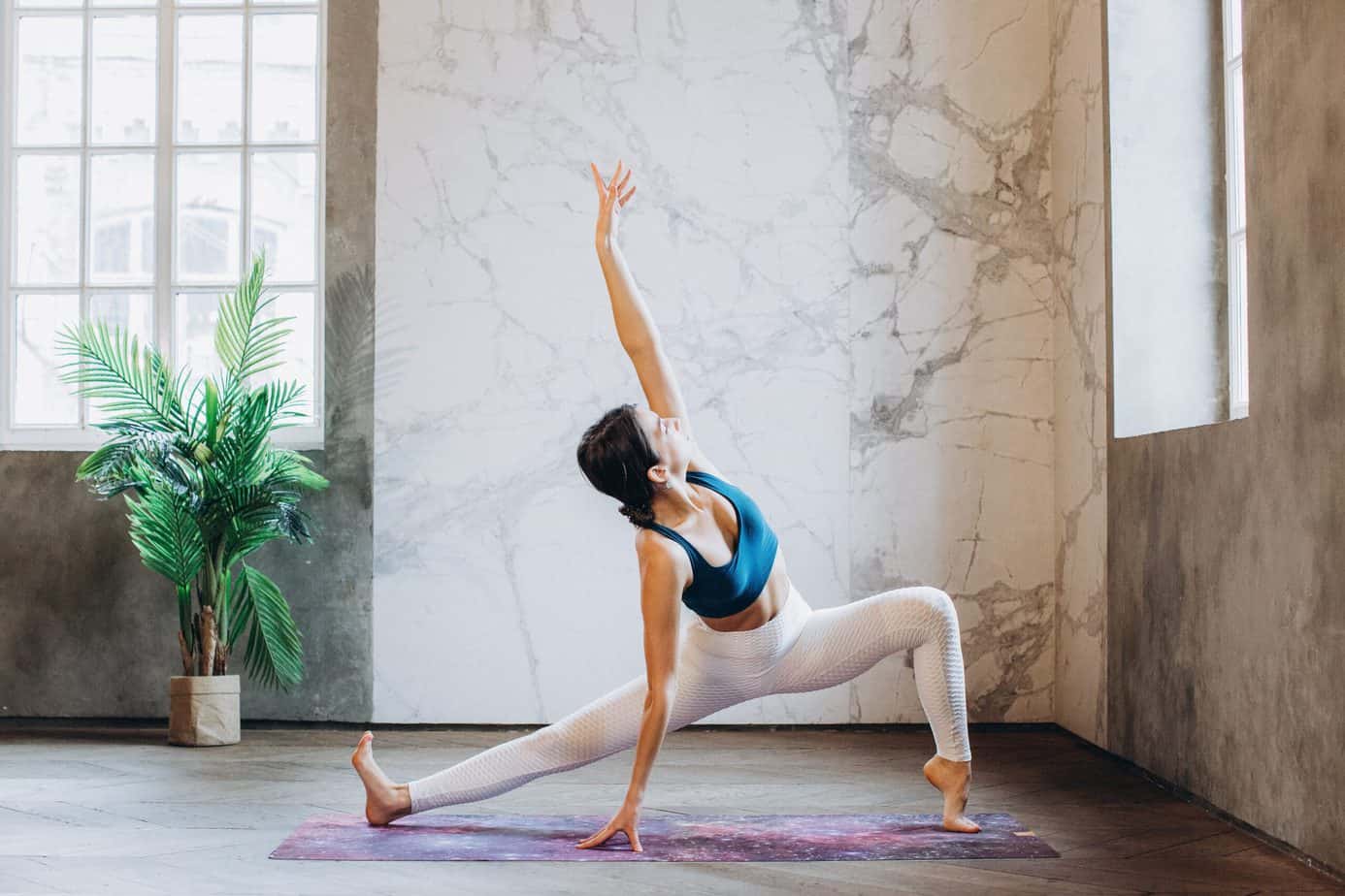 a woman wearing yoga pants stretching on a yoga mat