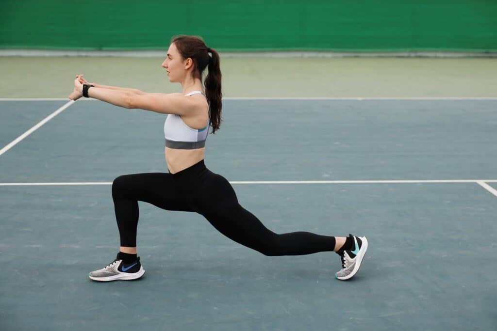 A woman doing lunges while wearing black leggings