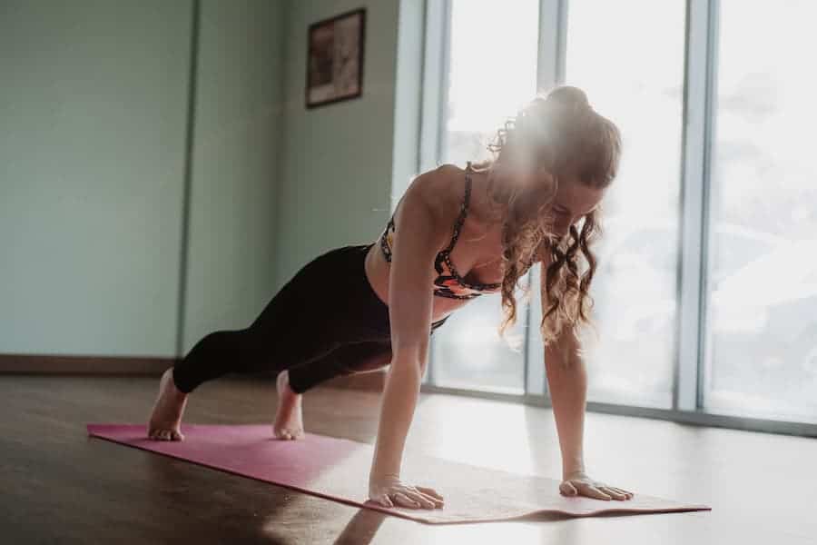 A woman doing push up while wearing leggings