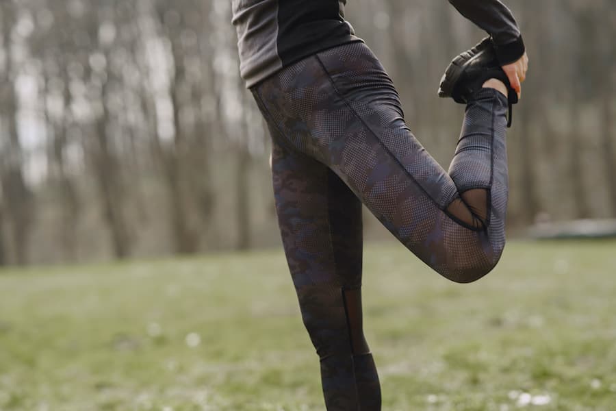 Woman with camouflage leggings stretching up