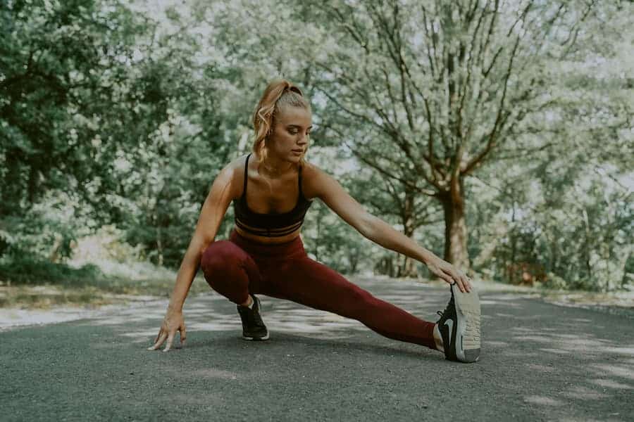 Woman stretching up with burgundy leggings