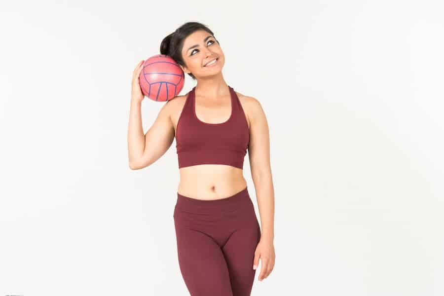 Woman in burgundy leggings whole holding a ball