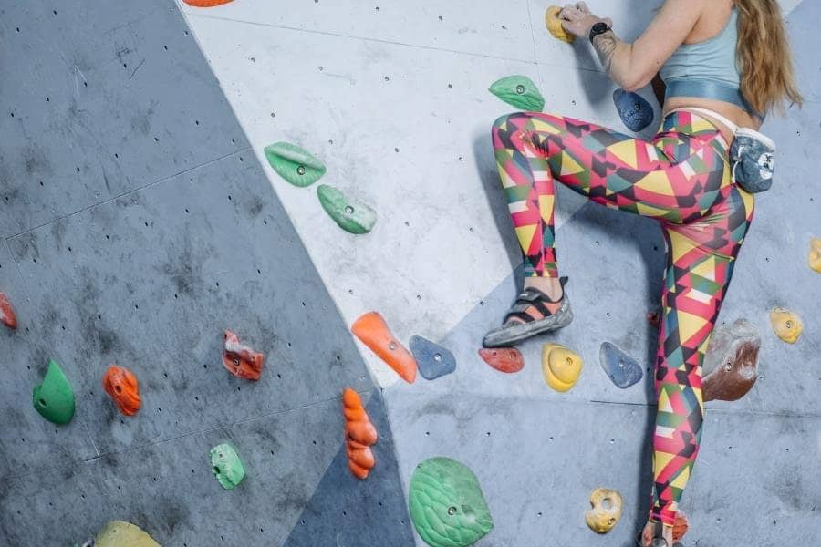 A girl wearing a colorful leggings to wall climb