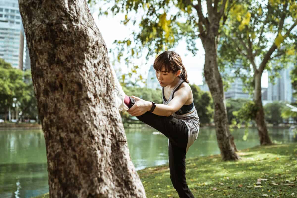 An image of a girl doing stretches while wearing leggings on a summer day