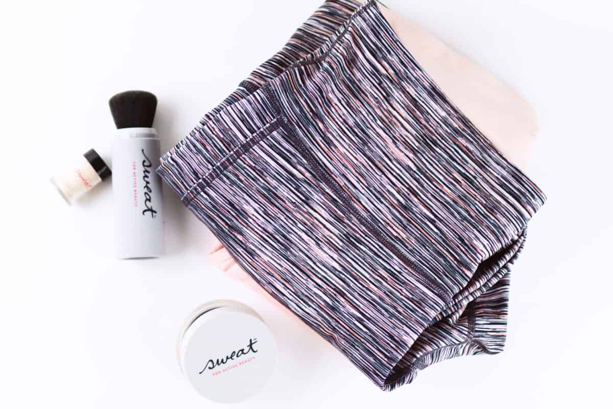 Colorful leggings placed near a black make-up brush and a white container on top of a white surface