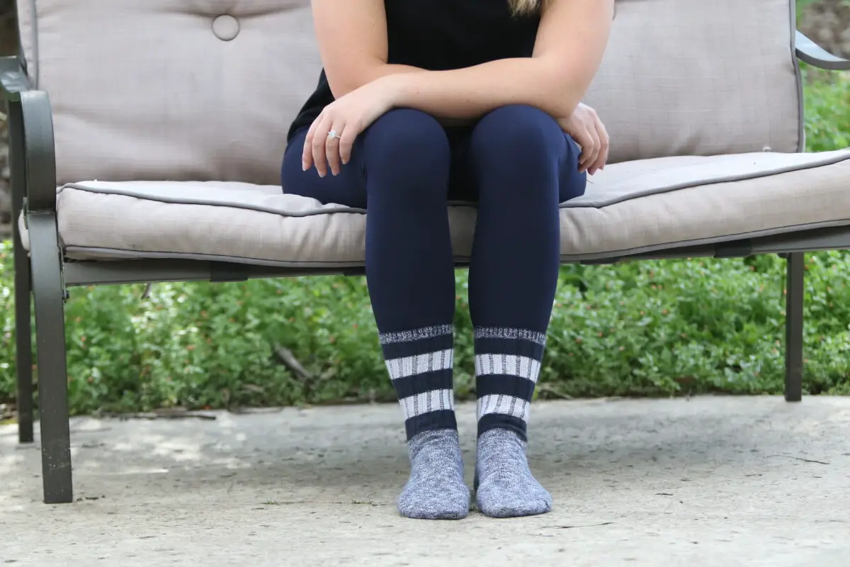 Woman in a blue leggings wearing gray socks sitting on a brown couch outside the house