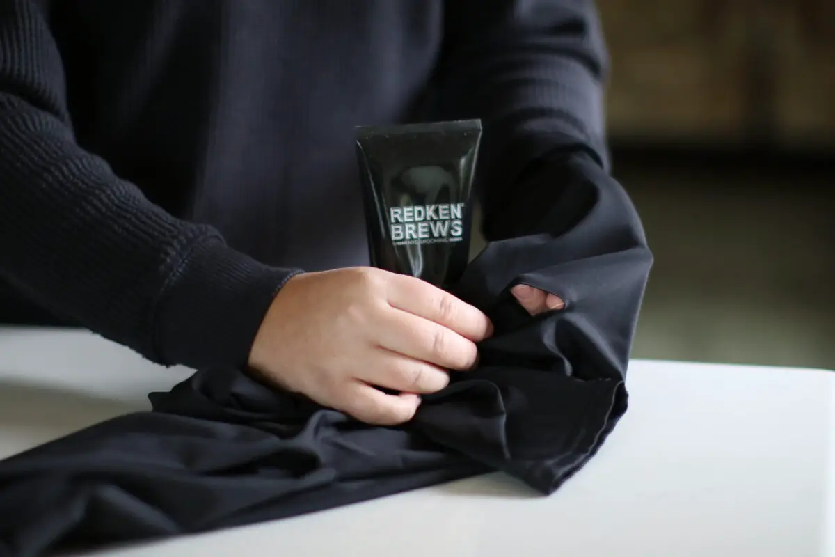 A person in dark blue long sleeves fixing black leggings with hair gel placed on a black pouch