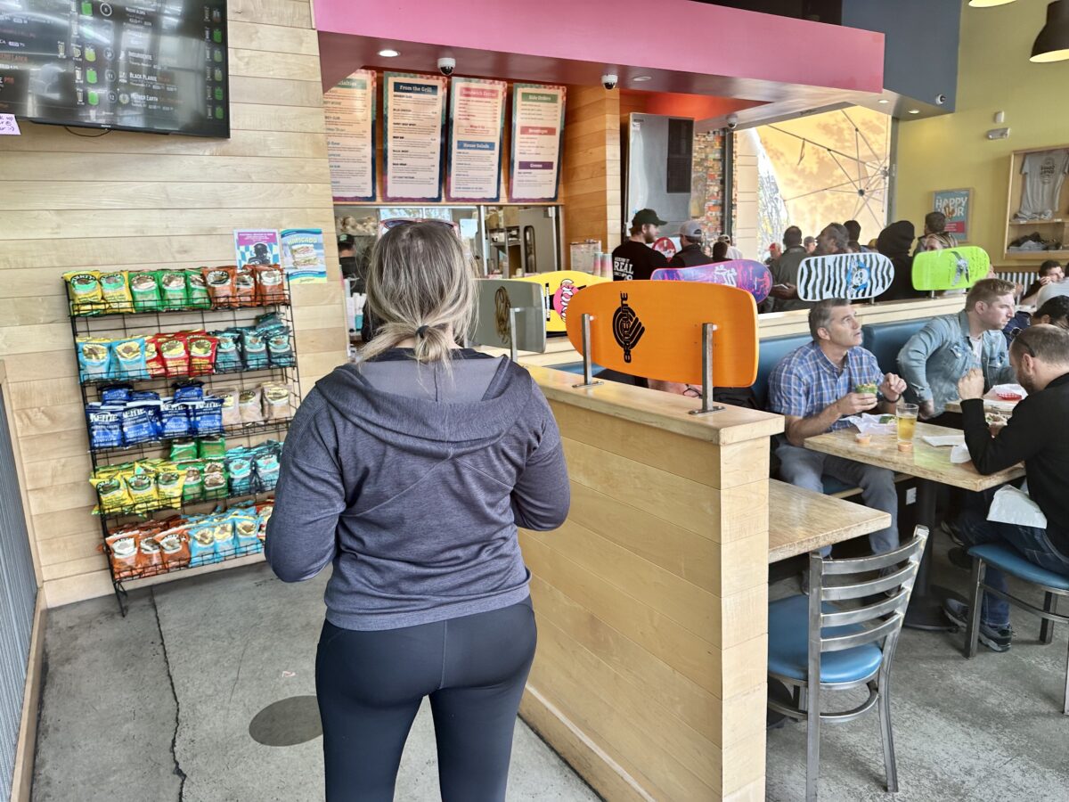 A woman in a gray jacket and black yoga pants is checking the menu at the restaurant