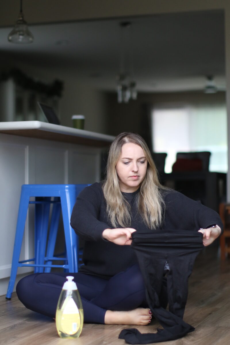 Baby shampoo placed on a bottle used by a woman to stretch black leggings