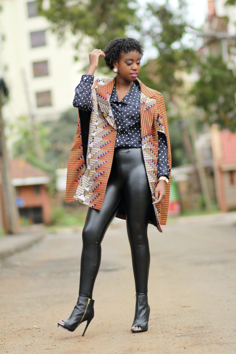 A woman wearing a polka dots top and black leggings posing on the street