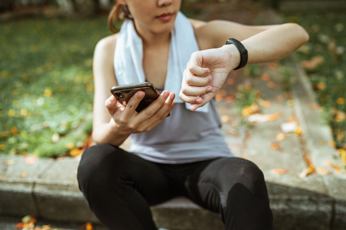 A woman wearing a gray tank top and black leggings seated on a cemented floor