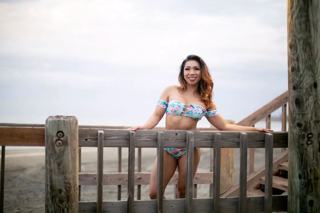Woman holding the fence of a bridge while posing with her blue printed two piece bikini