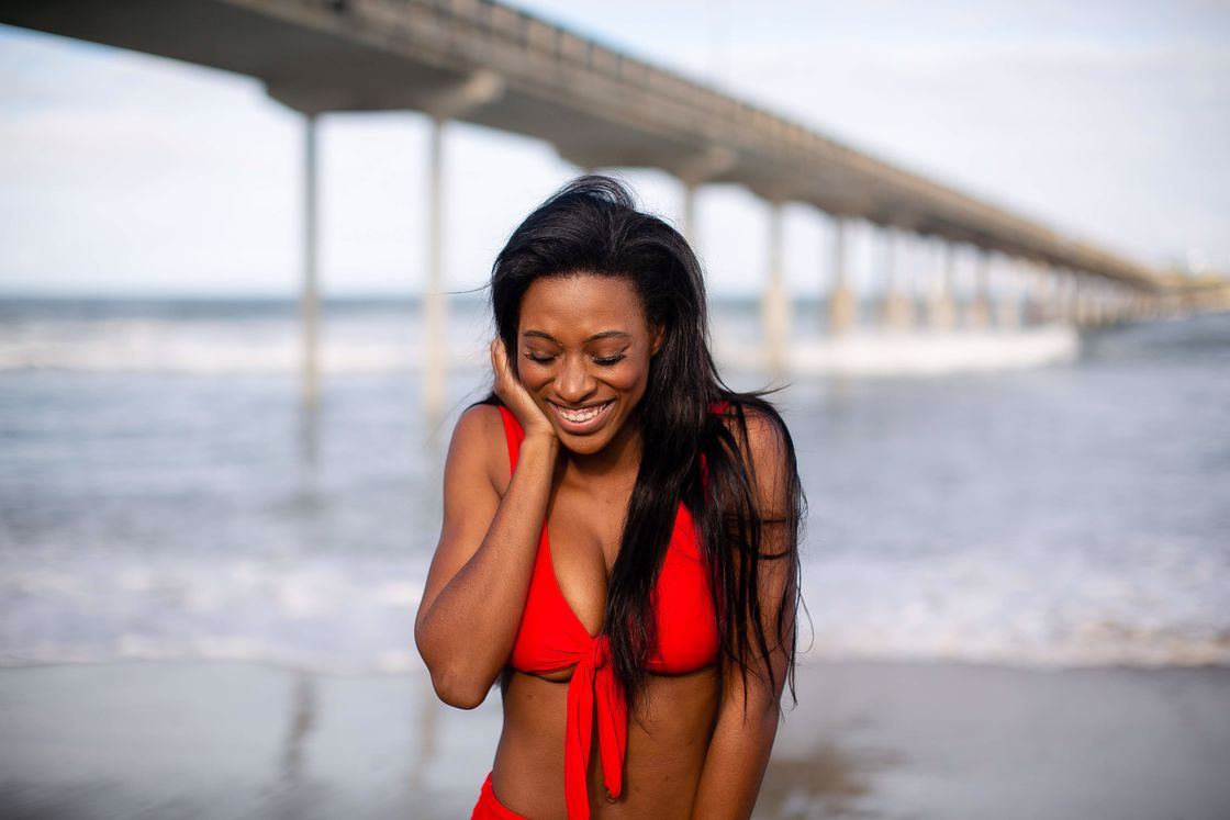 Woman smiling with her hand against her cheeks while wearing a two piece red bikini