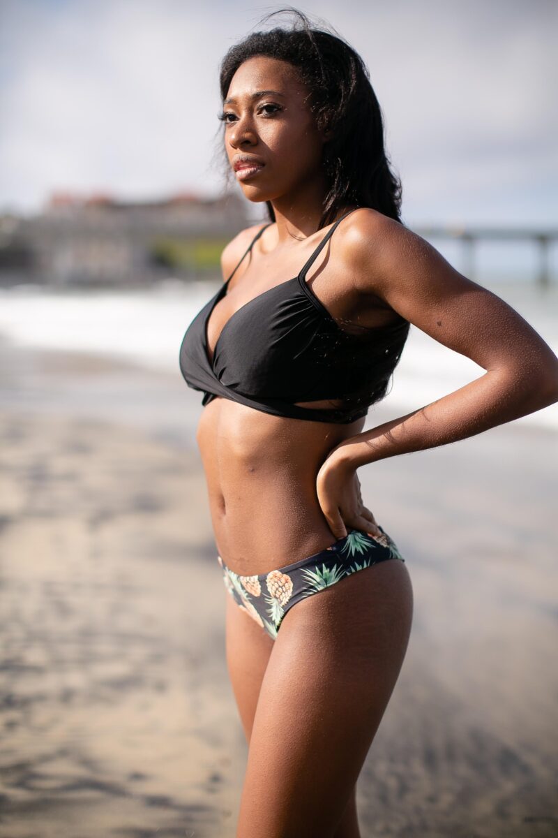 A black push-up bikini top and black underwear with a fruit design are worn by a woman
