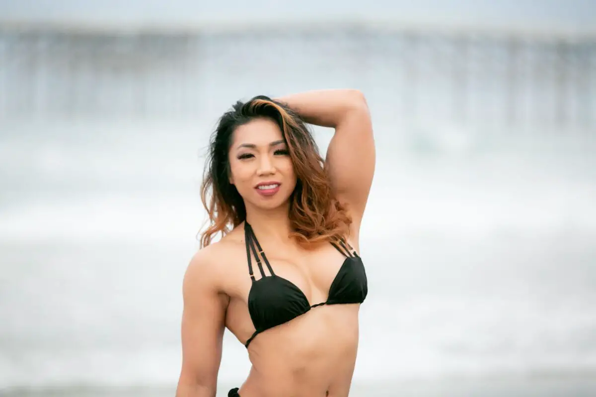 A woman wearing a black halter bikini top and black underwire on the beach