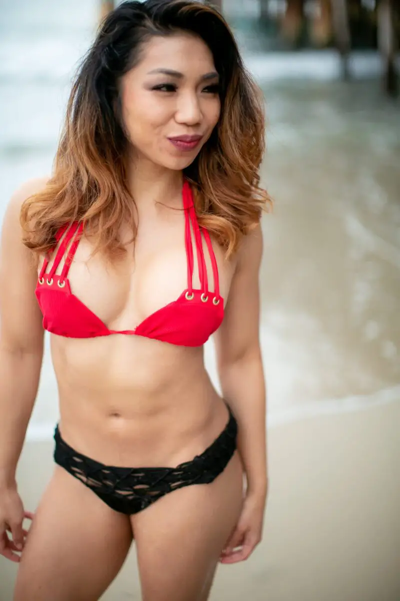 A red bikini top and black underwear are worn by a woman on the beach