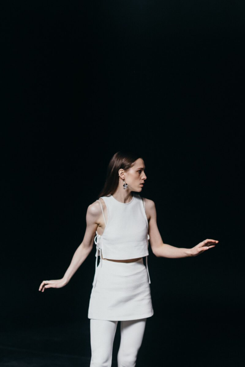 A woman in white sleeveless wearing a white skirt and white leggings