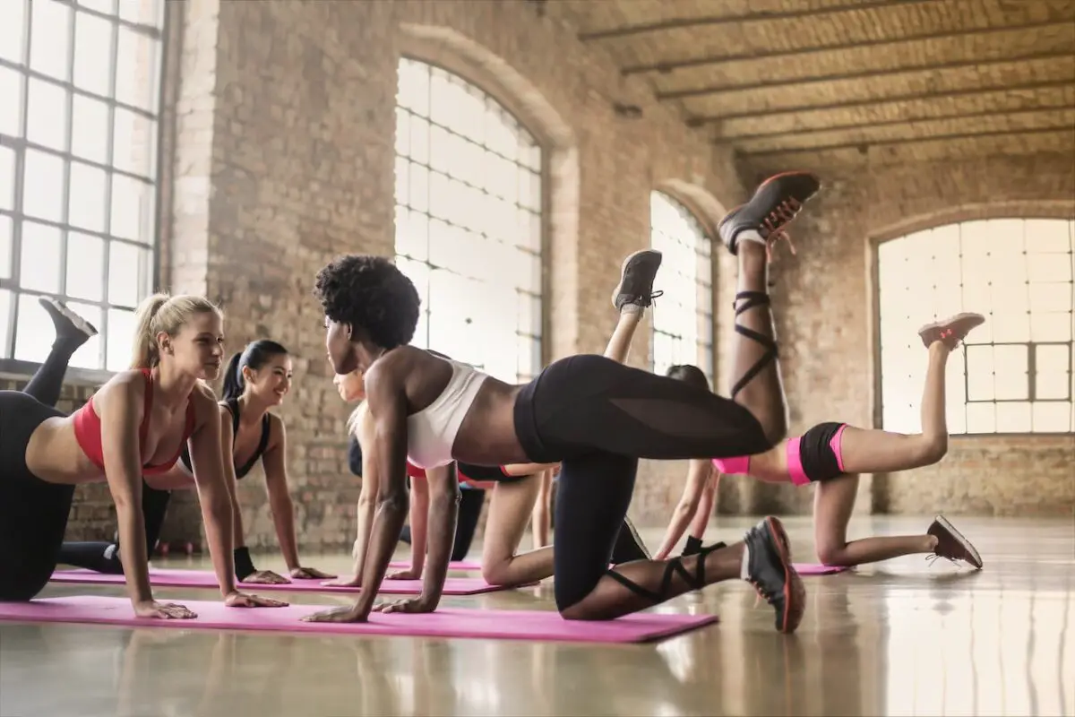 Women wearing sports bras and leggings doing yoga on the pink yoga mat