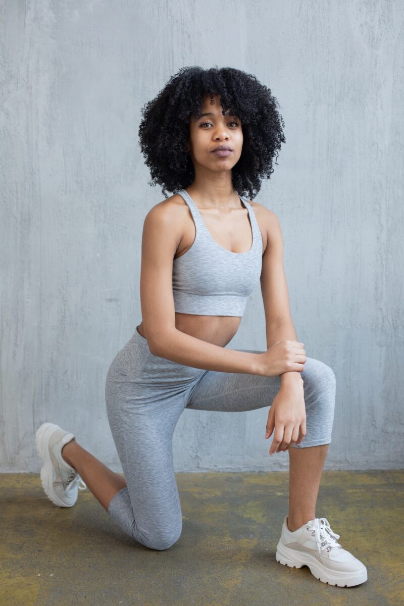 A woman wearing gray sports bra and leggings doing stretching