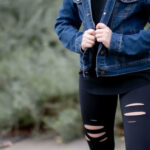 Woman wearing a blue jean jacket and black ripped leggings