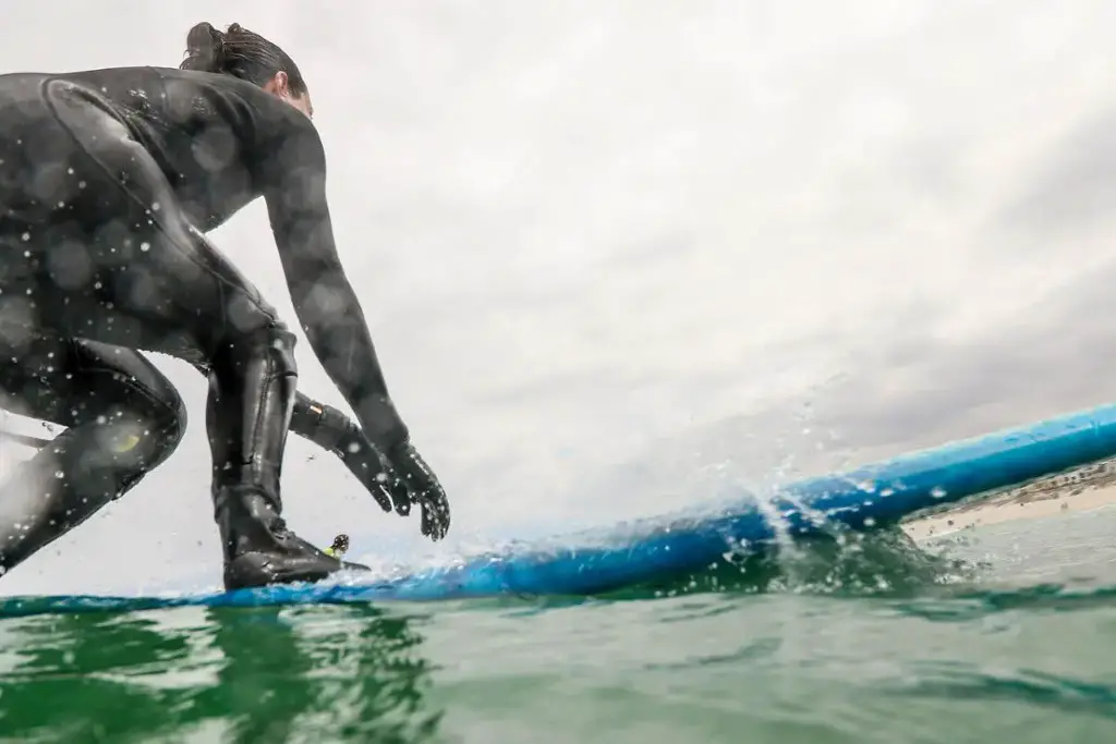 Woman wearing a black wetsuit while riding her surfboard to catch some waves