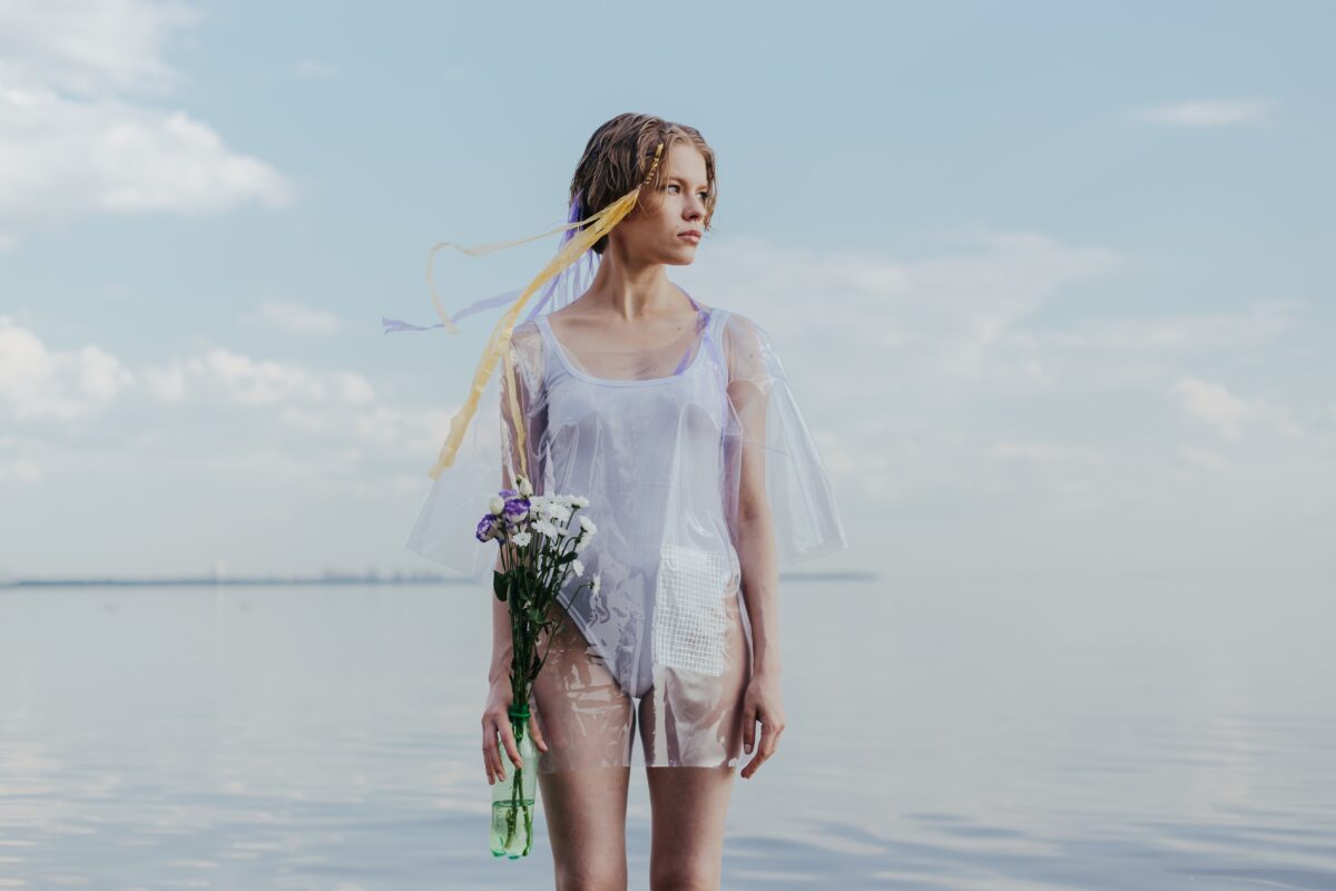 A woman with white one-piece swimsuit holding flowers